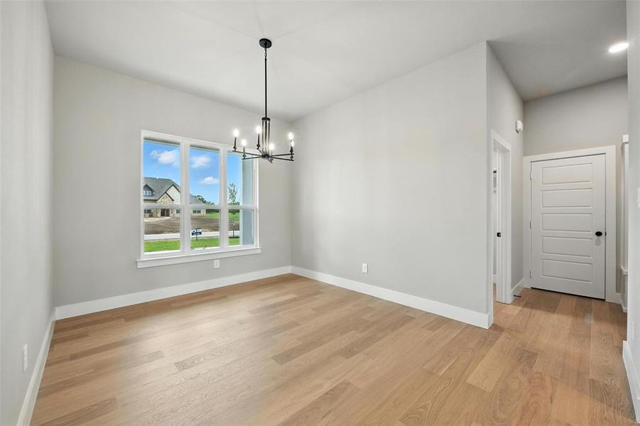 Empty room with light wood finished floors and a chandelier Empty room with light wood finished floors and a chandelier