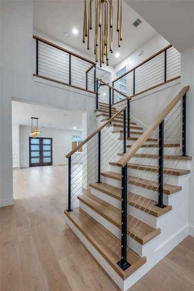 Stairway featuring wood finished floors, a towering ceiling, and recessed lighting