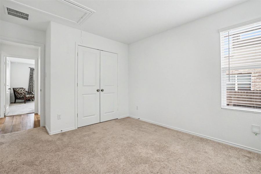 Carpeted room featuring a double-door closet with spherical hardware, white walls, and a window with blinds