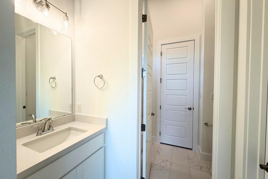 Bathroom vanity featuring an integrated rectangular sink, light-toned countertop, and brushed nickel faucet