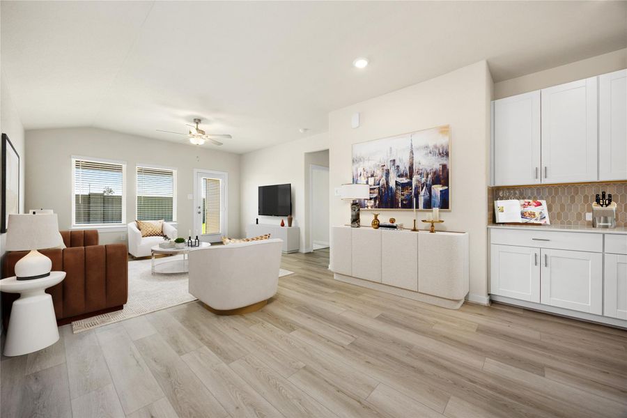 This inviting living area is filled with natural light, complemented by neutral tones and luxury vinyl plank flooring. The open layout flows effortlessly into the kitchen, creating a warm and functional space for relaxing or connecting with family.