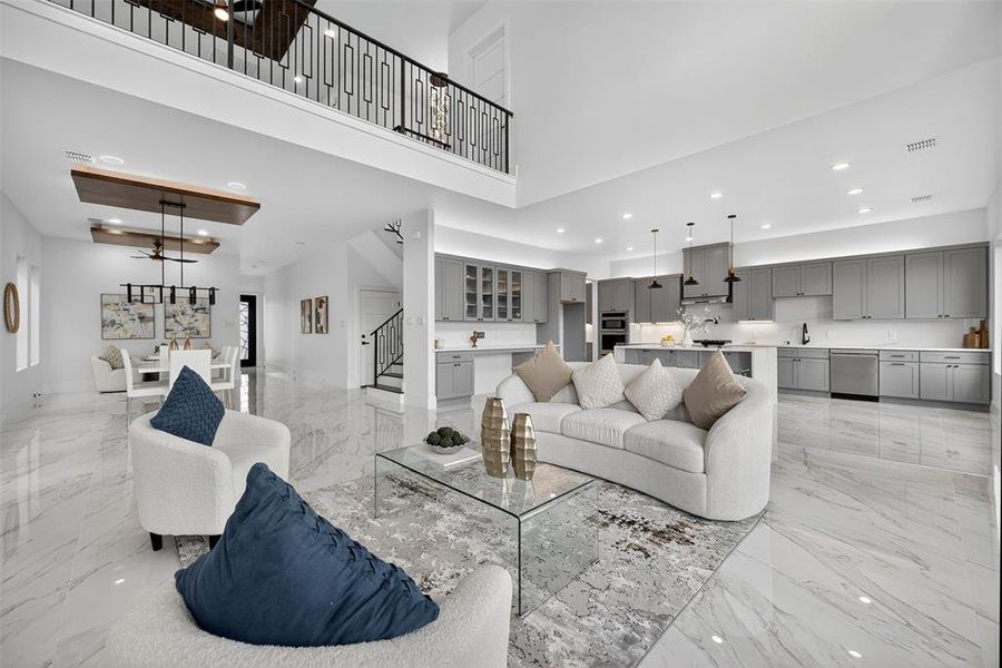 Living room featuring recessed lighting, stairs, ceiling fan, a high ceiling, and light marble finish floors
