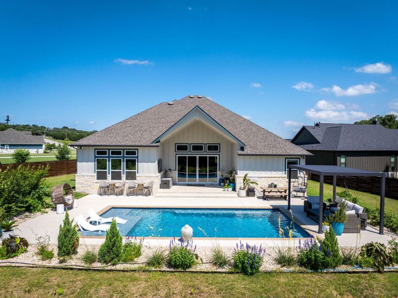 An inviting backyard oasis awaits with a sparkling pool and a comfortable patio for outdoor relaxation.