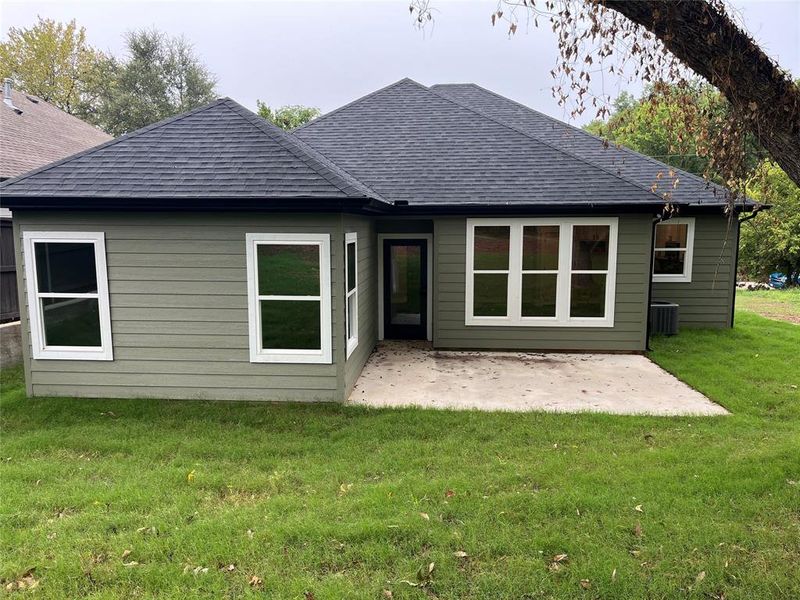 Rear view of property with a patio, a yard, and a shingled roof Rear view of property with a patio, a yard, and a shingled roof