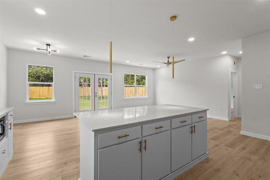 Kitchen island featuring a light-toned countertop, ample storage cabinetry, and gold-finish hardware