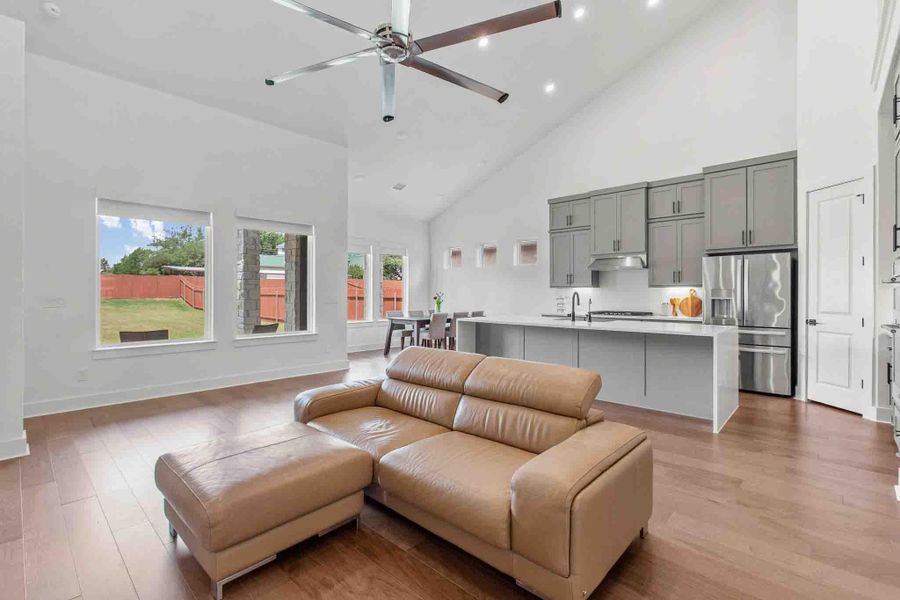 Vaulted ceilings accentuate this open-concept living space, featuring wood-finish flooring and a contemporary ceiling fan