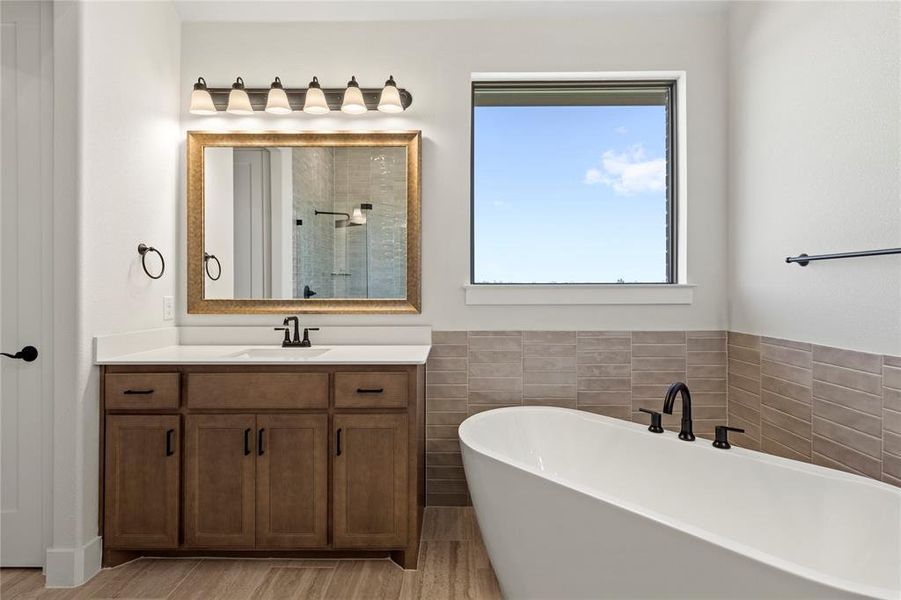 Bathroom featuring hardwood / wood-style flooring, vanity, and shower with separate bathtub