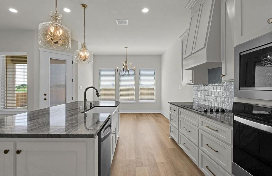 Kitchen with black appliances, dark stone countertops, decorative light fixtures, white cabinets, and recessed lighting
