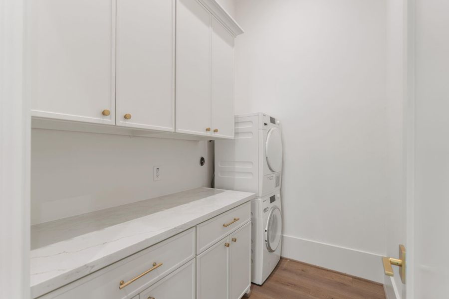 The utility room features built-in cabinetry, a long countertop for folding, and dedicated space for full-size appliances. Clean lines and efficient layout make this space both practical and polished.