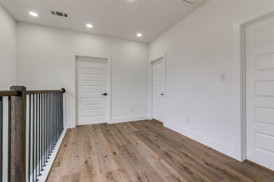 Upstairs landing featuring wood finished floors, visible vents, recessed lighting, and baseboards