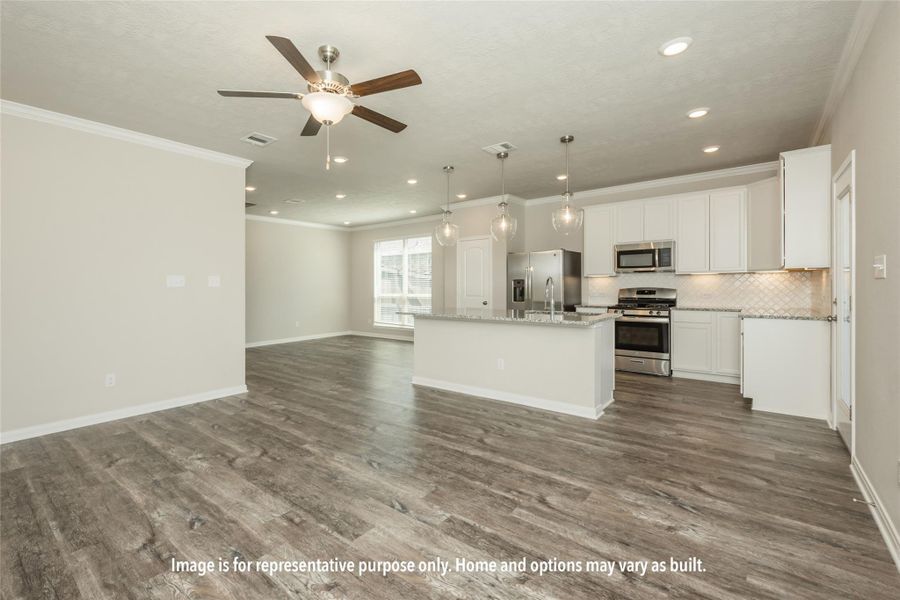 Kitchen with open floor plan, white cabinets, appliances with stainless steel finishes, decorative light fixtures, and decorative backsplash