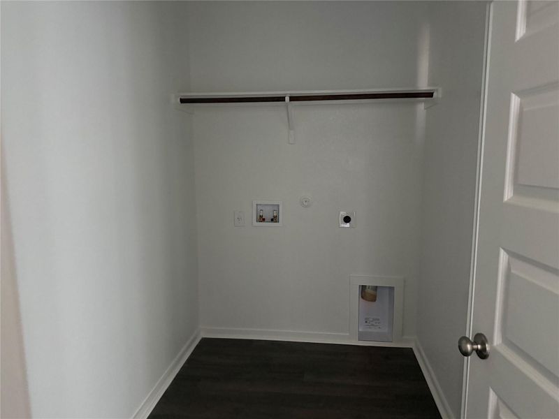 Dark wood-look flooring contrasts beautifully with crisp white walls in this practical laundry area.
