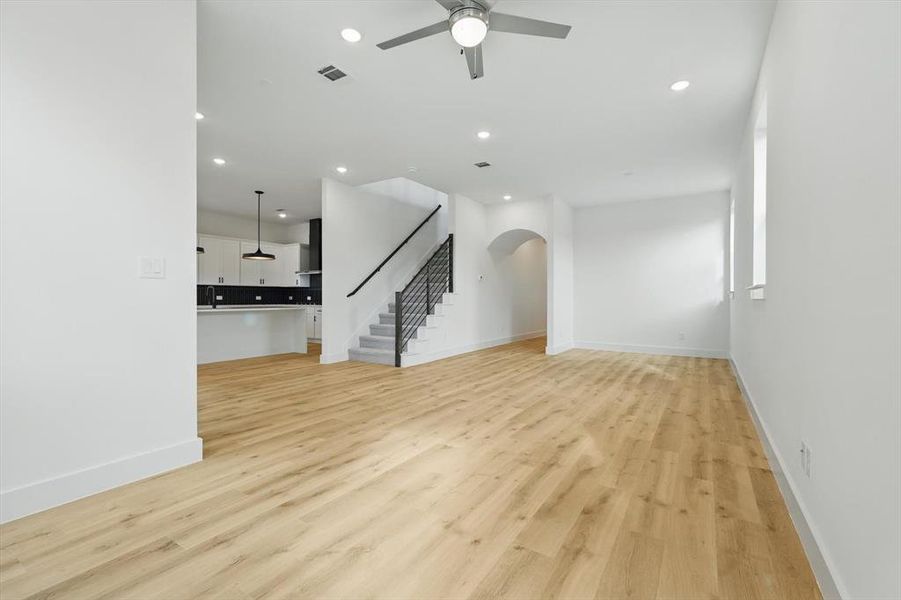 Unfurnished living room featuring stairway, a ceiling fan, recessed lighting, arched walkways, and baseboards