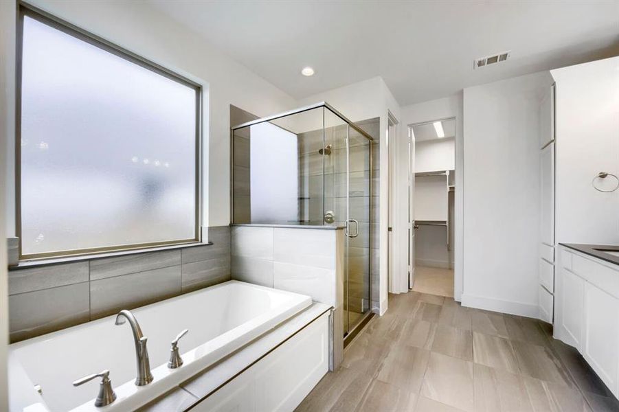 Contemporary bathroom featuring a built-in tub with brushed nickel fixtures, a glass-enclosed shower, and a large frosted window Contemporary bathroom featuring a built-in tub with brushed nickel fixtures, a glass-enclosed shower, and a large frosted window