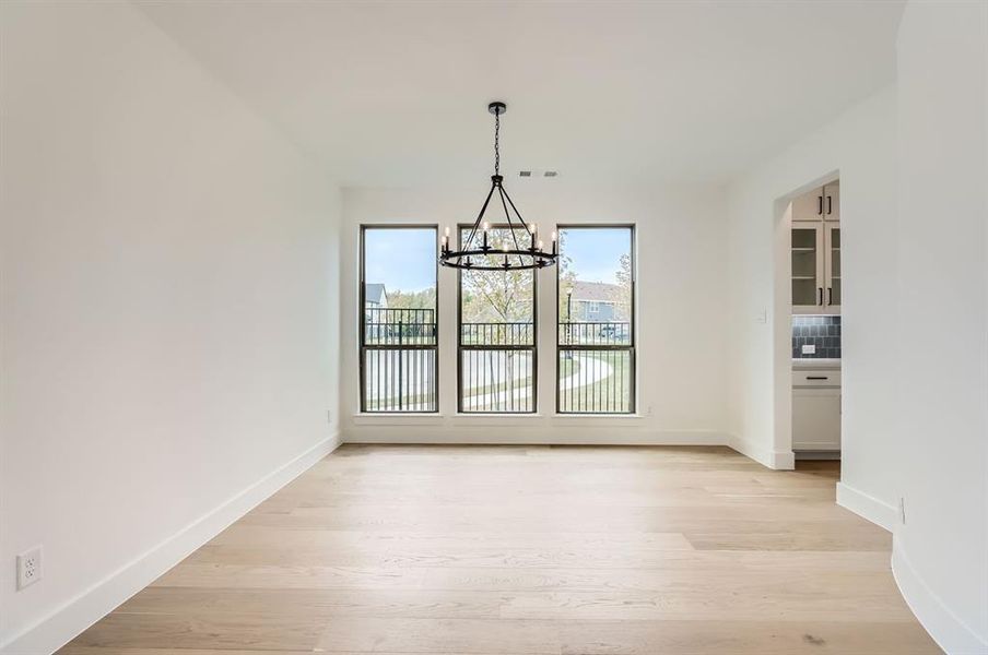 Unfurnished dining area featuring an inviting chandelier and light wood-type flooring