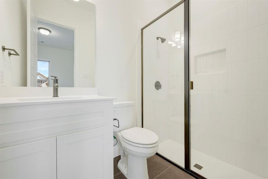 Full bath featuring a stall shower, vanity, and dark tile patterned floors Full bath featuring a stall shower, vanity, and dark tile patterned floors
