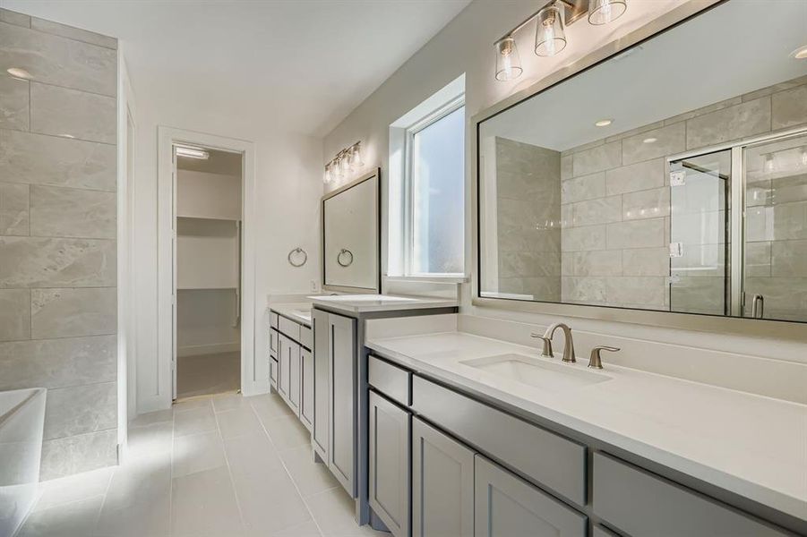 Bathroom featuring a shower stall, two vanities, and light tile patterned floors Bathroom featuring a shower stall, two vanities, and light tile patterned floors
