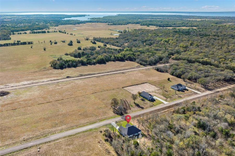 Breathtaking aerial vista capturing the property's exceptional location with distant lake views on the horizon. Surrounded by rolling farmland and established trees, this prime lot offers the perfect balance of privacy, natural beauty, and open space—a truly rare find in today's market.