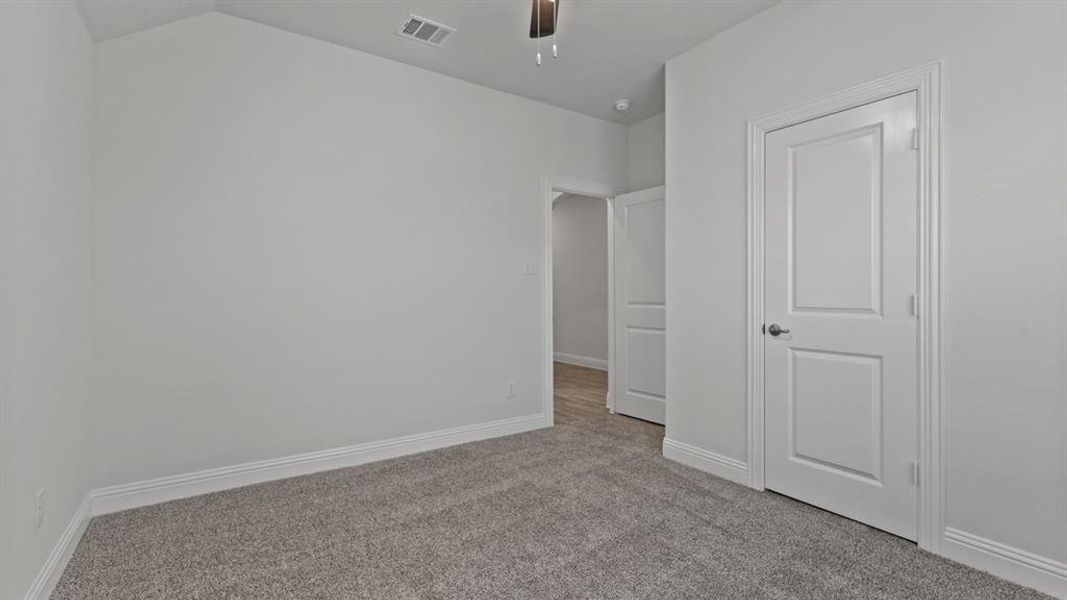 Unfurnished bedroom featuring carpet, vaulted ceiling, and ceiling fan