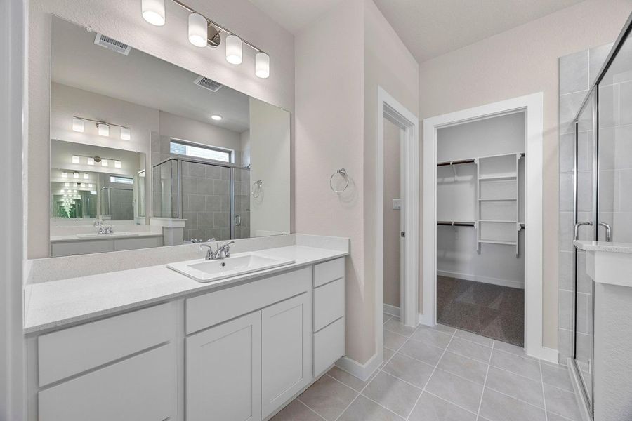 A well-lit bathroom with a spacious vanity, walk-in shower, and an adjacent walk-in closet. A well-lit bathroom with a spacious vanity, walk-in shower, and an adjacent walk-in closet.