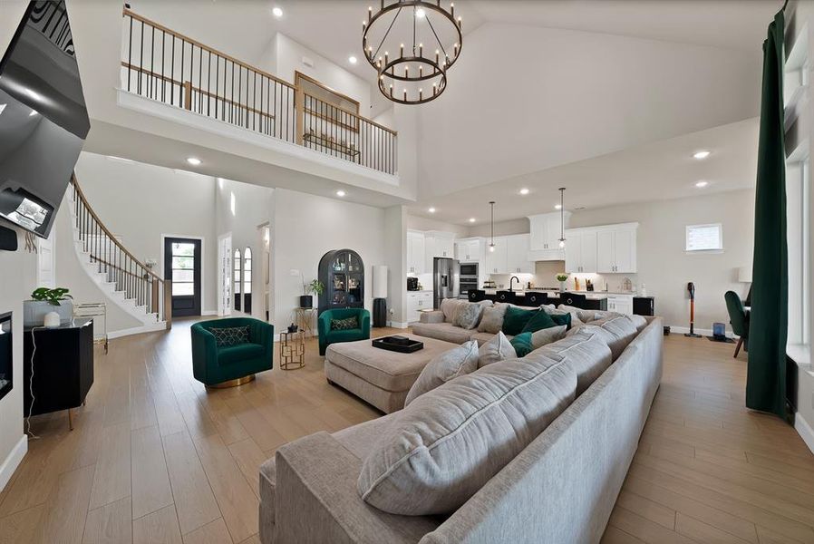 Expansive living space featuring a soaring vaulted ceiling and wood-finish flooring Expansive living space featuring a soaring vaulted ceiling and wood-finish flooring