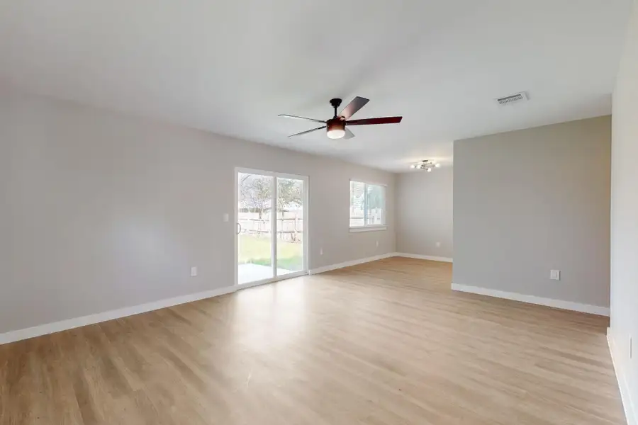 Unfurnished room with light wood finished floors, ceiling fan, baseboards, and visible vents