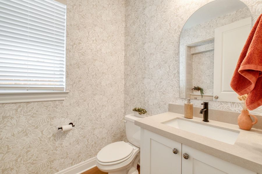 Even the powder room gets some personality with botanical wallpaper and an arched mirror.
