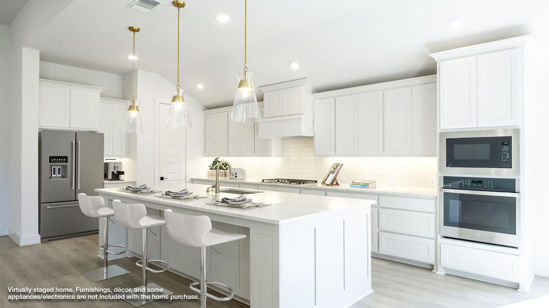 Kitchen with a kitchen breakfast bar, appliances with stainless steel finishes, a kitchen island with sink, light wood-style floors, and lofted ceiling