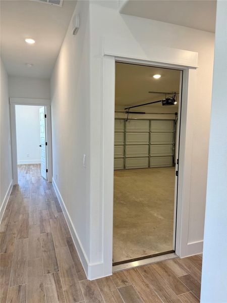 Hallway with light wood-type flooring and recessed lighting