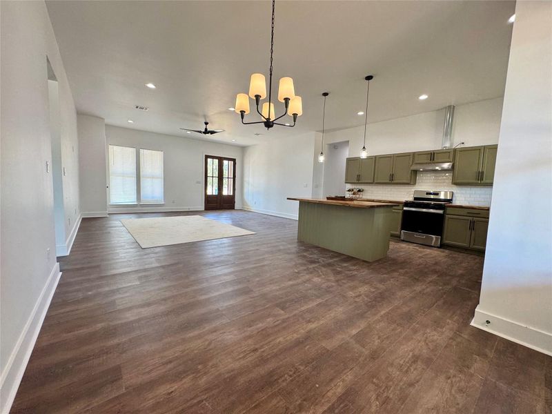Kitchen featuring green cabinets, a chandelier, hanging light fixtures, a center island, and stainless steel range with gas stovetop Kitchen featuring green cabinets, a chandelier, hanging light fixtures, a center island, and stainless steel range with gas stovetop