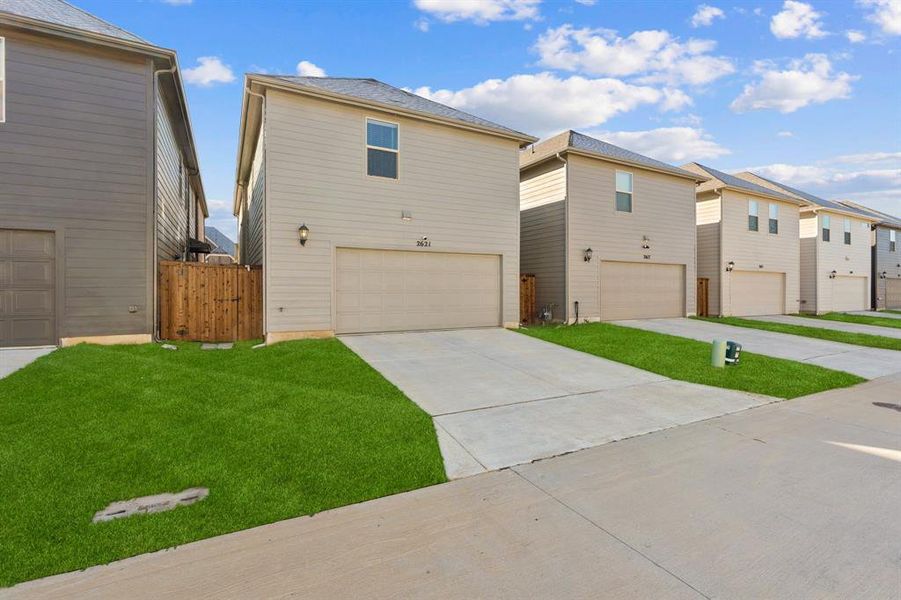 View of front of house featuring concrete driveway, an attached garage, a residential view, and a front lawn