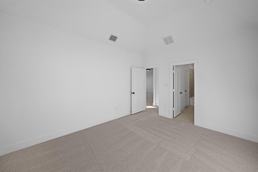 Unfurnished bedroom with light carpet and vaulted ceiling