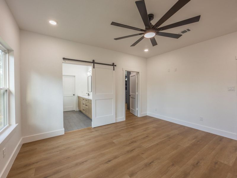 A custom sliding barn door separates the bedroom from the ensuite bath, blending rustic charm with modern convenience for a seamless, private retreat. A custom sliding barn door separates the bedroom from the ensuite bath, blending rustic charm with modern convenience for a seamless, private retreat.
