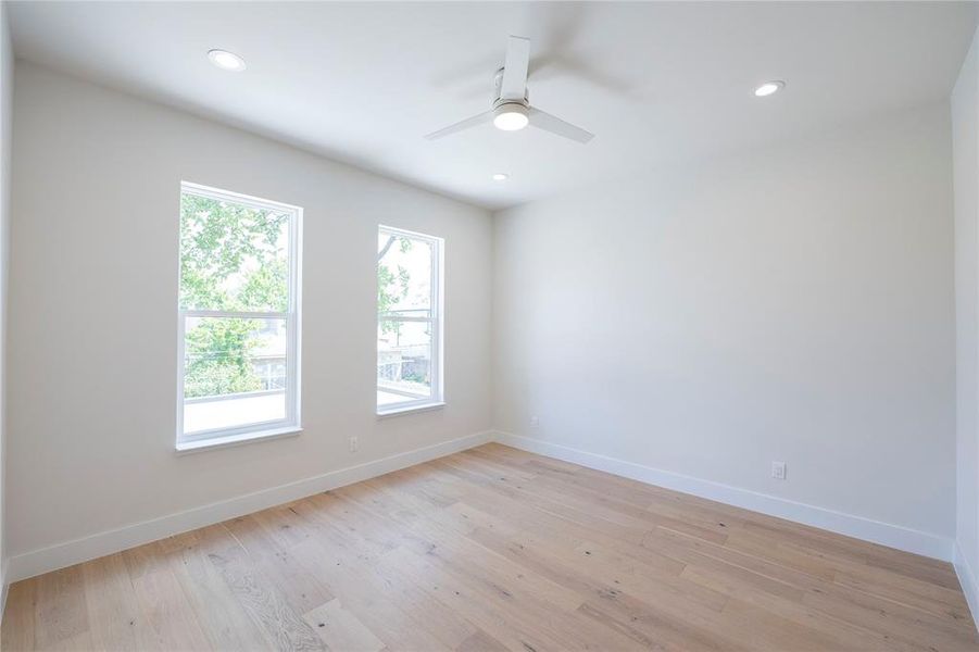 Empty room with ceiling fan and light hardwood / wood-style floors