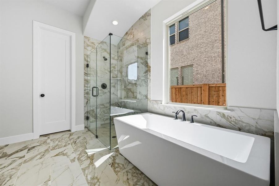 Bathroom featuring light marble finish floors, a marble finish shower, a freestanding bath, tile walls, and recessed lighting