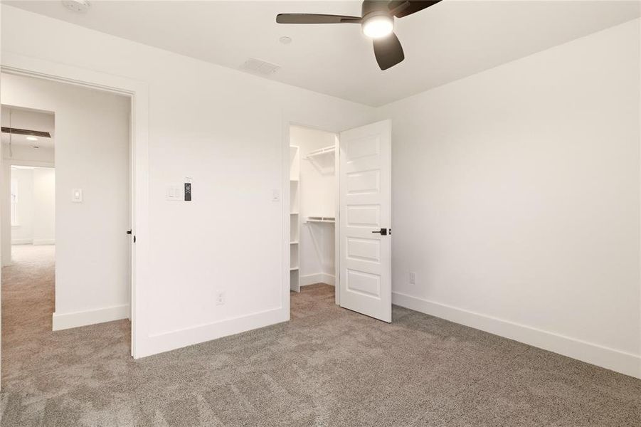 Unfurnished bedroom featuring carpet floors, a spacious closet, and ceiling fan