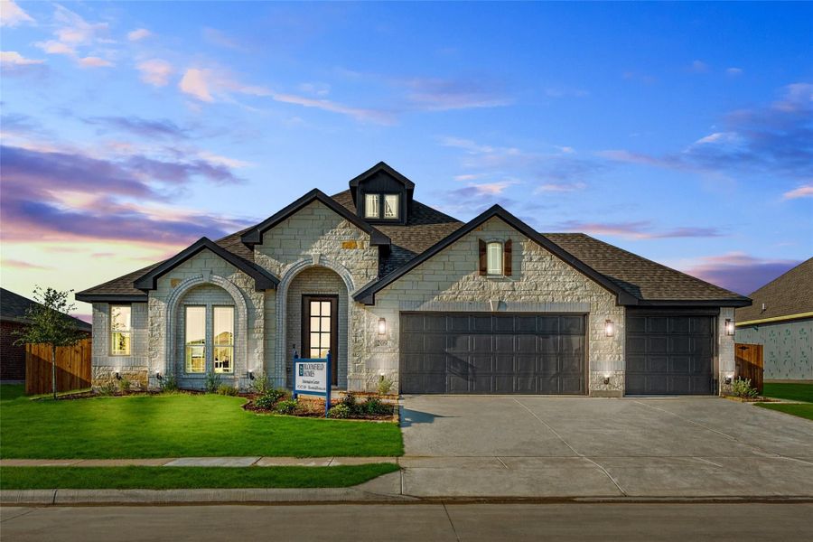 Single-story stone home with arched entry, two-car garage, and manicured front lawn at dusk