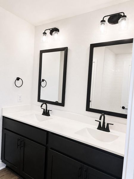 Primary bathroom featuring dual sinks, modern black matte finishes, a spacious vanity, and a clean, spa-like design.