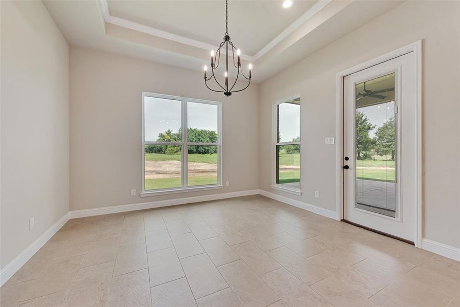 Unfurnished dining area featuring a chandelier, crown molding, and a raised ceiling