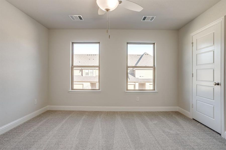 Unfurnished room with light colored carpet and a ceiling fan