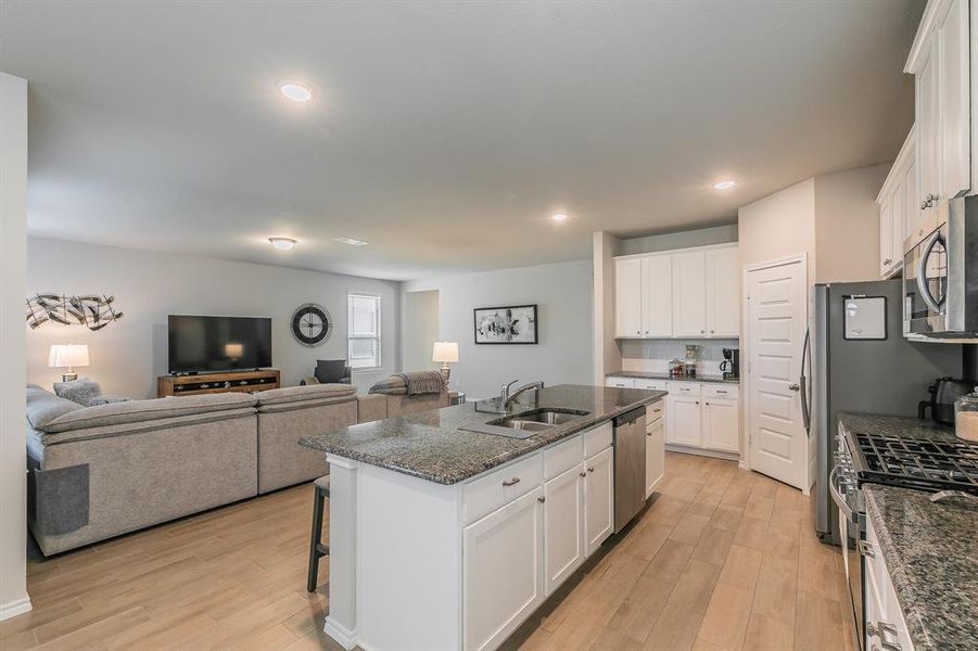 Kitchen featuring stainless steel appliances, light wood-style flooring, a breakfast bar area, a center island with sink, and recessed lighting