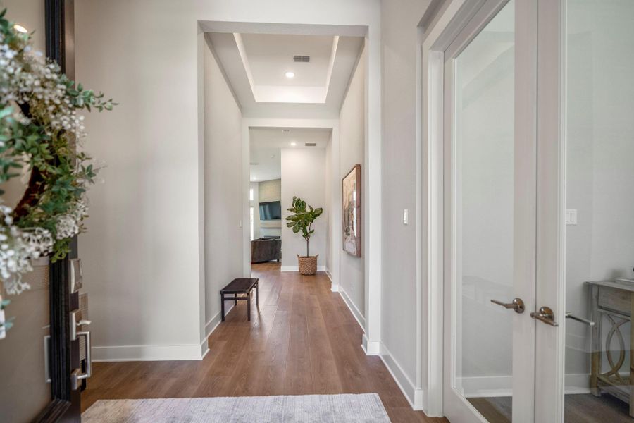 Step into a bright, polished foyer where LVP flooring, neutral finishes and a raised ceiling lead the way toward open airy living spaces.