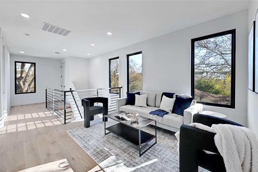 Living room featuring recessed lighting, visible vents, light wood-style flooring, and baseboards