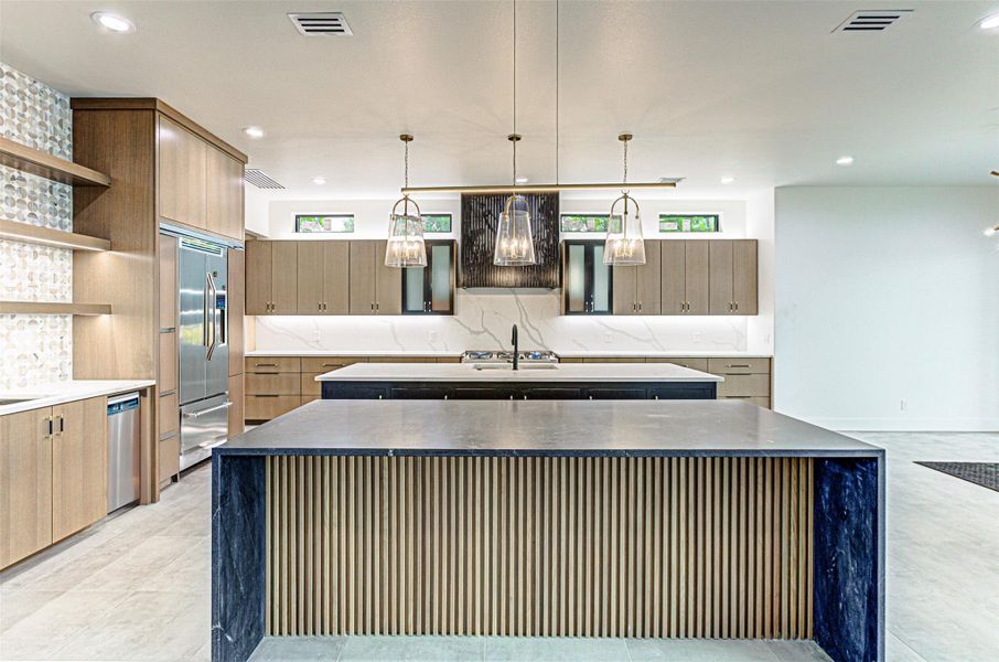 Kitchen with stainless steel appliances, open shelves, a center island with sink, and visible vents
