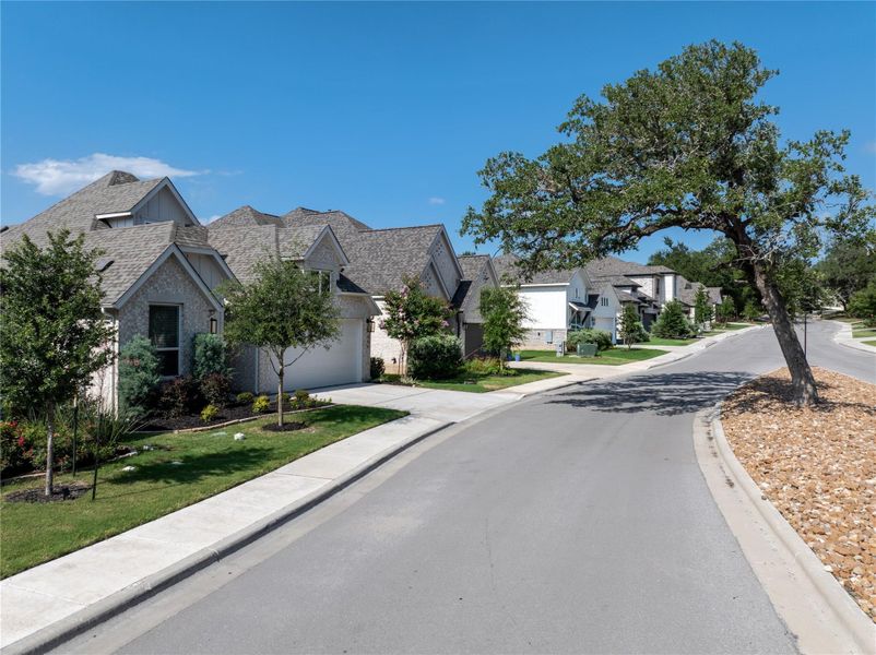 A tranquil neighborhood street winds through a community of elegant homes with well-maintained landscapes. A tranquil neighborhood street winds through a community of elegant homes with well-maintained landscapes.