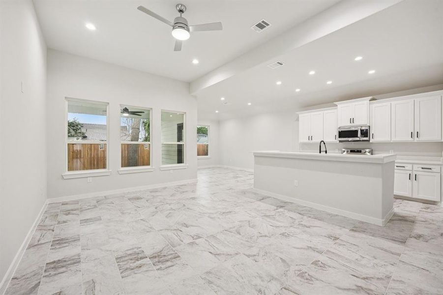 Kitchen featuring stainless steel microwave, ceiling fan, open floor plan, light marble finish flooring, and recessed lighting Kitchen featuring stainless steel microwave, ceiling fan, open floor plan, light marble finish flooring, and recessed lighting