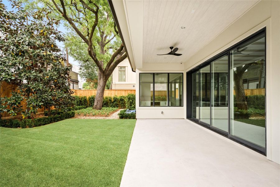 Seamless indoor-outdoor living with expansive sliding doors opening to a covered patio and manicured yard, offering room for a future pool.