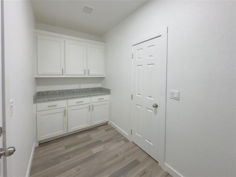 Laundry area with light hardwood / wood-style flooring