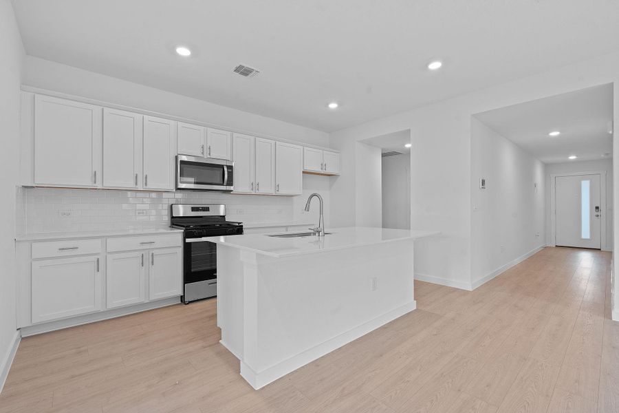 Kitchen featuring stainless steel appliances, backsplash, light wood-type flooring, white cabinetry, and recessed lighting