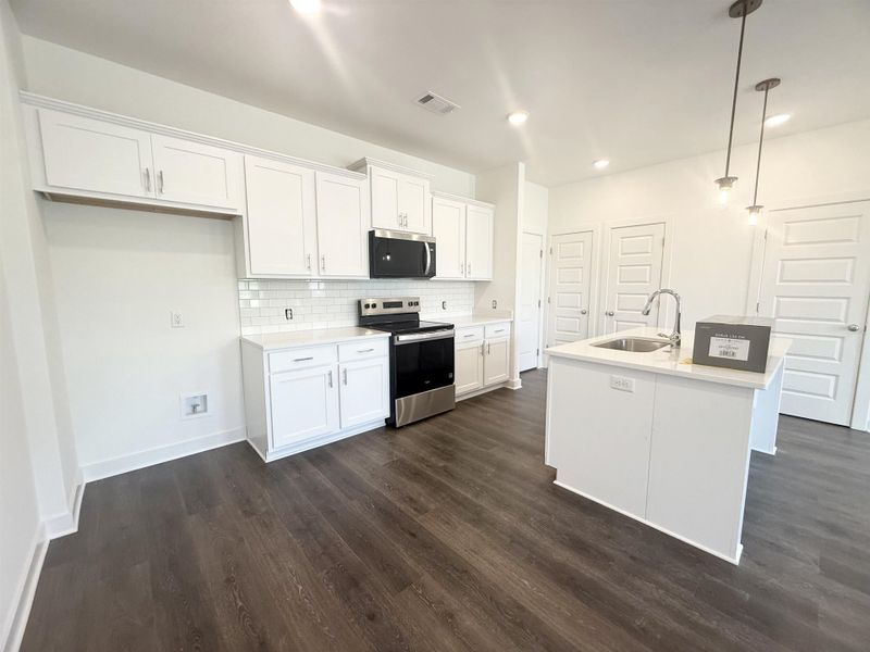 Kitchen featuring stainless steel appliances, backsplash, hanging light fixtures, white cabinetry, and recessed lighting
